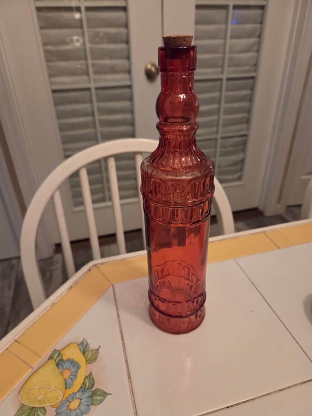 Red glass decorative bottle with an embossed vintage style pattern and cork